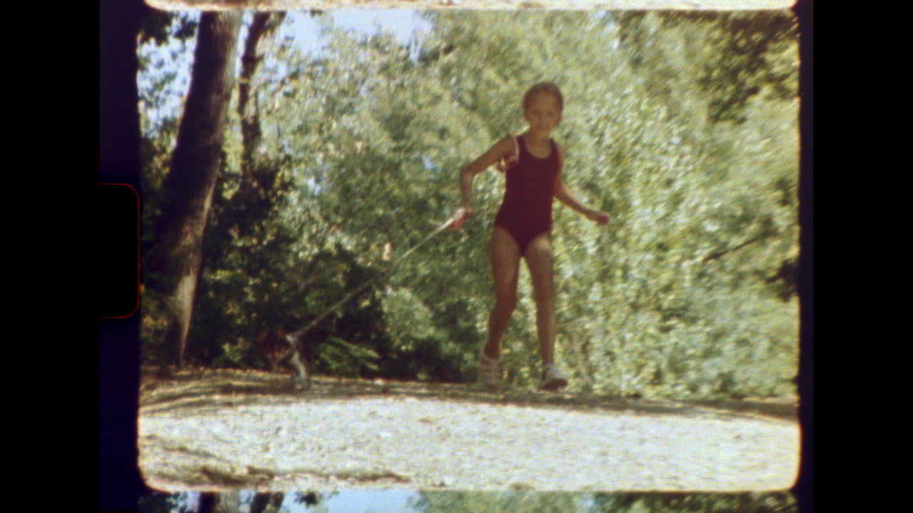 Vintage 8mm girl walking small dog on sunny forest trail