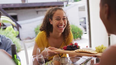 mujer latina feliz sosteniendo bandeja con bocadillos, con diversos amigos en la fiesta de la cena en el patio