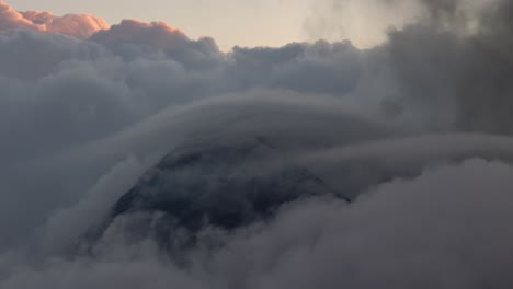 Volcano Fuego cone visible in cloud at dawn, drone view above clouds