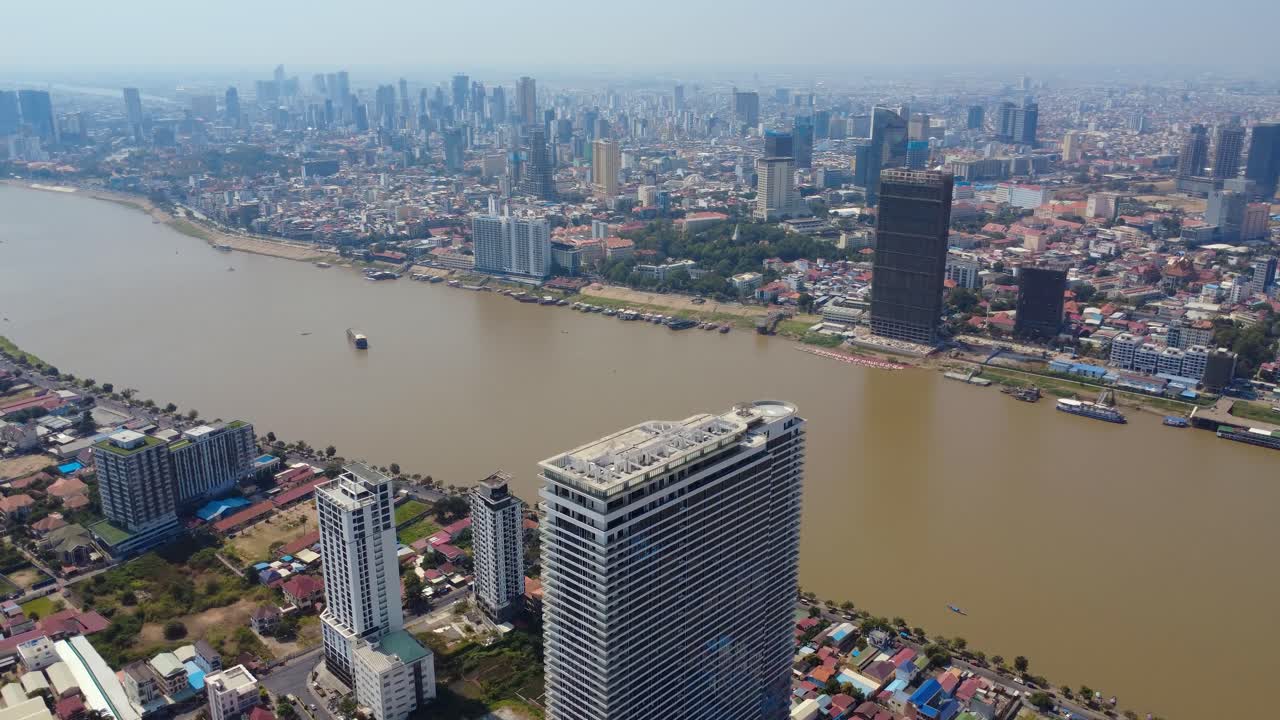 Phnom Penh Mekong riverfront buildings and development, Urban populated city under hazy sky due to air pollution, Drone shot