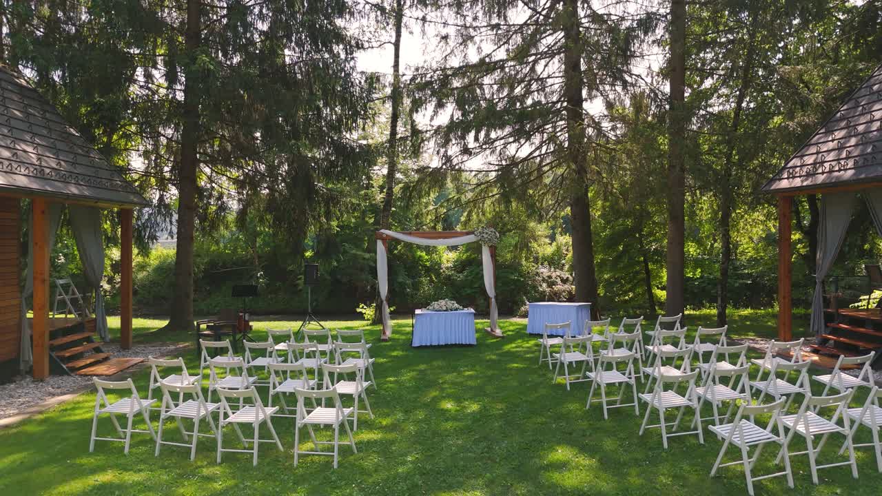 White chairs and stage are ready outside for the wedding ceremony.