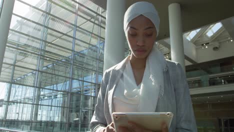 mujer de negocios usando una tableta en un edificio de oficinas moderno