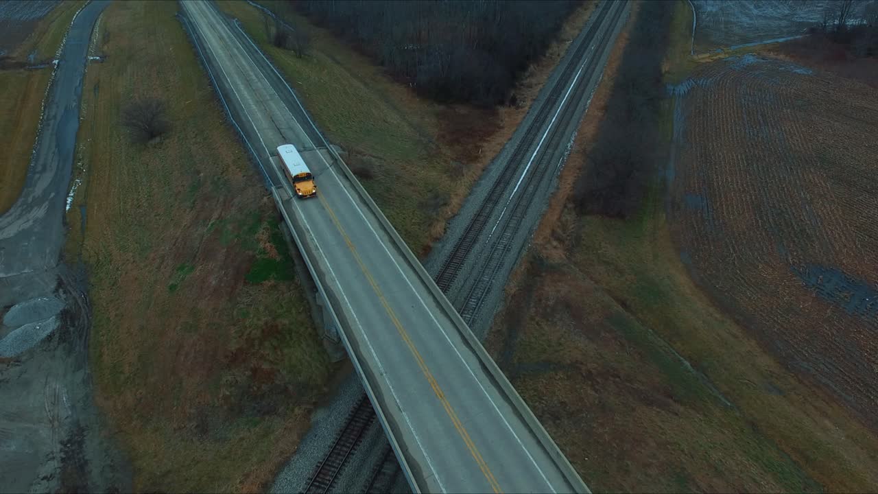 Auto, camion e un autobus che viaggiano su un cavalcavia sopra i binari ferroviari, accanto a uno stagno, su un'autostrada rurale dell'Illinois.