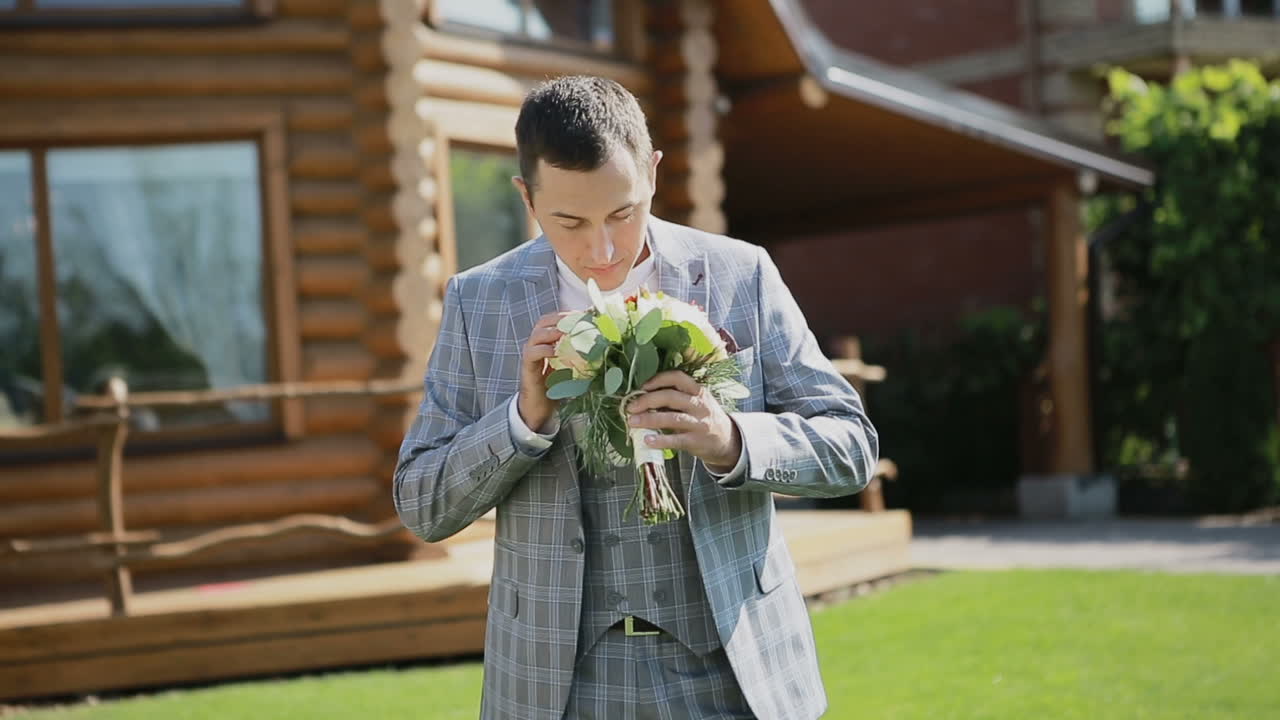 Young man with flowers. Groom holding wedding bouquet.