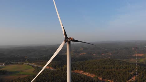 A-Damaged-And-Burned-White-Windmill-Steadily-Overlooking-The-Beautiful-Countryside-Landscape-Of-Aljezur,-Portugal---Aerial-Shot