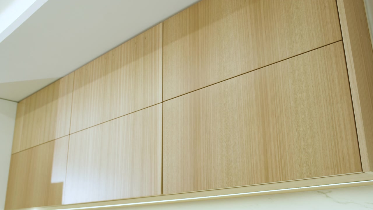 Inquadratura di mobili contenitori sospesi con finitura liscia in legno chiaro, con linee rette e giunzioni precise.
