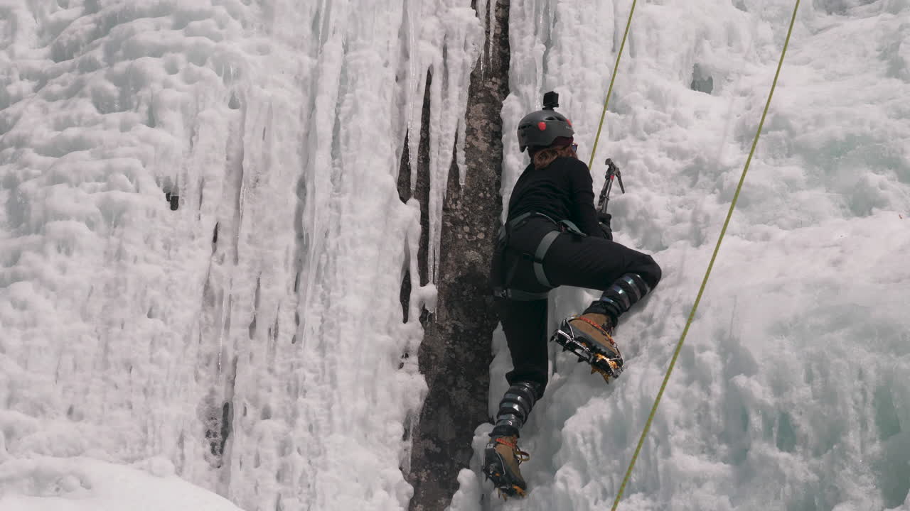 A female ice climber taking on the challenge of a vertical frozen ice wall