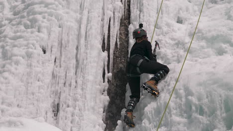 a female ice climber taking on the challenge of a vertical frozen ice wall