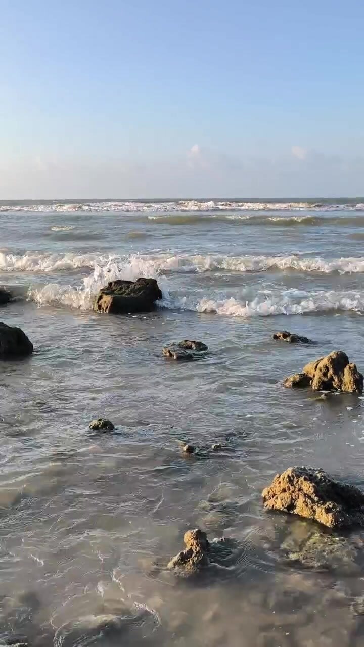Onde dell'oceano che si infrangono contro le rocce su una spiaggia soleggiata