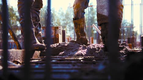 two construction builders holding the concrete hose, unloading concrete on site