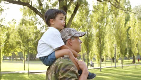 happy little boy riding dad's shoulders in park