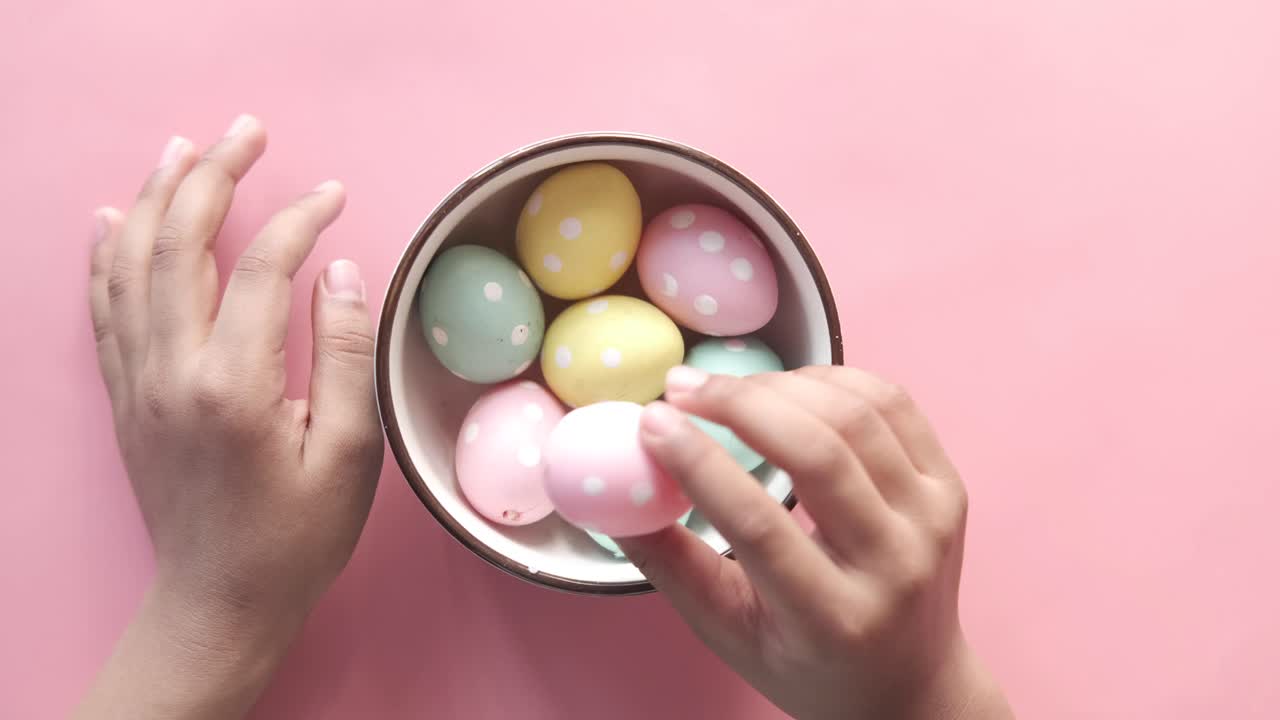 las manos de los niños recogiendo huevos de pascua de un cuenco