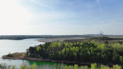 drone fly above green pine tree forest approaching coal plant power station at distance in konin poland
