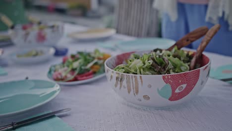 a bowl of healthy green salad beautifully presented on a dinner table adorned with colorful tableware