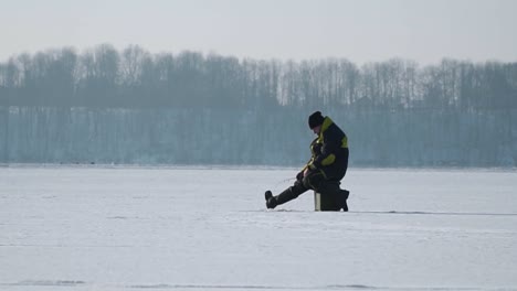 Silhouette-Fischer-Auf-Dem-Eis-An-Einem-Zugefrorenen-See-Im-Winter