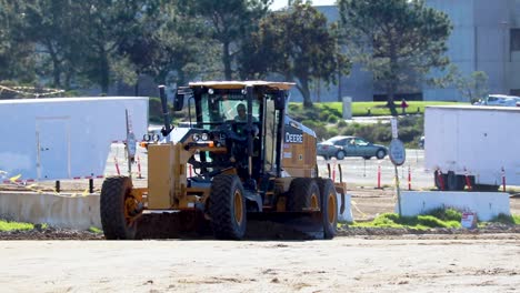 a yellow road grader smoothing out uneven ground