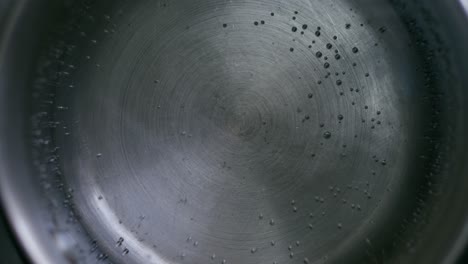 a close-up top view of water boiling in a metal pot on the stove