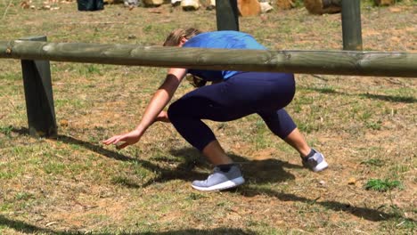 Woman-crawling-under-the-hurdle-during-obstacle-course