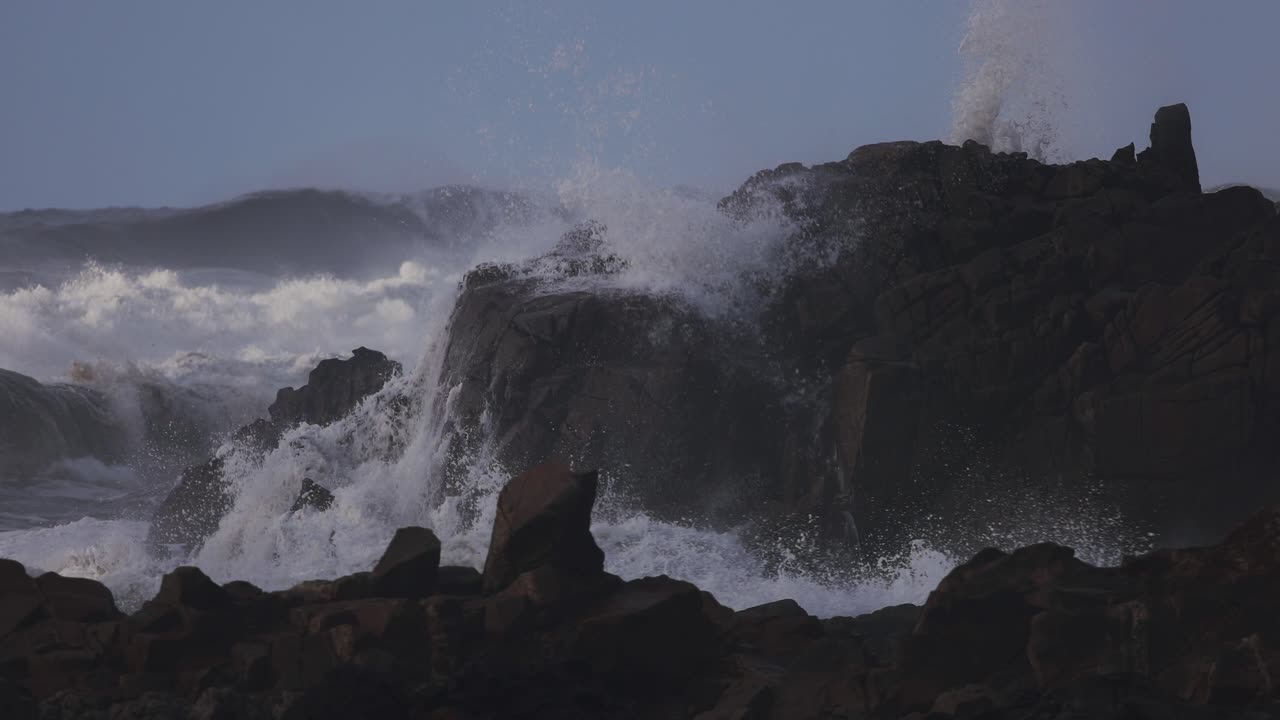 Waves crashing into the rocks on a beach in slow motion