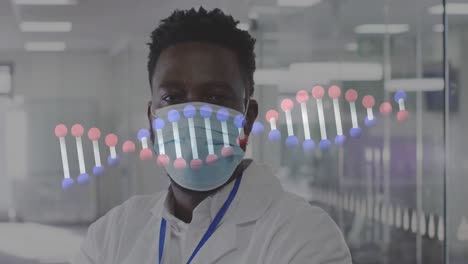 Animation-of-dna-helix-rotating-over-portrait-of-african-american-male-doctor-wearing-mask