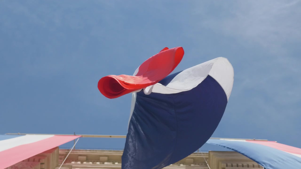 Close view of a large French flag banner whipping in the wind on a building facade, Cannes, France