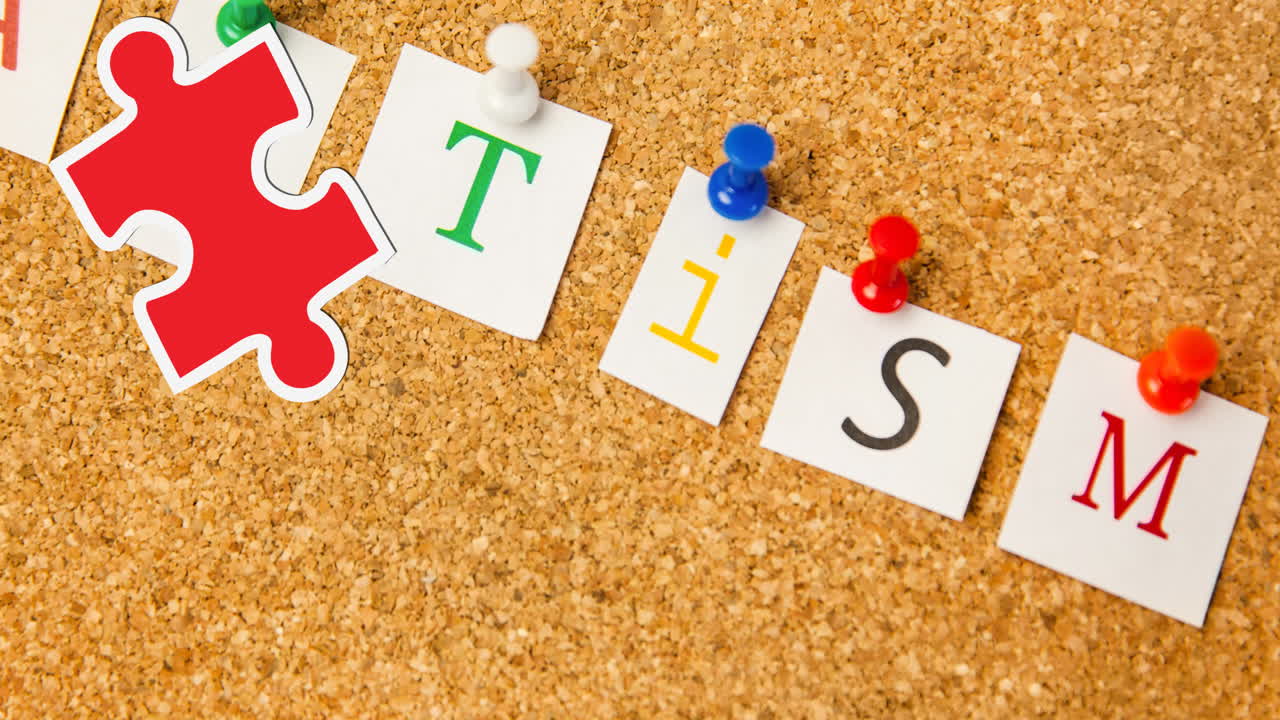 animación de piezas de rompecabezas rojas y amarillas que caen sobre el texto del autismo fijado en el tablero de corcho