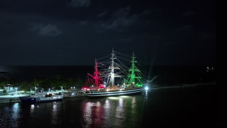 amerigo vespucci sailing ship illuminated at night with colors of italian flag and moored at punta torrecilla, santo domingo in dominican republic