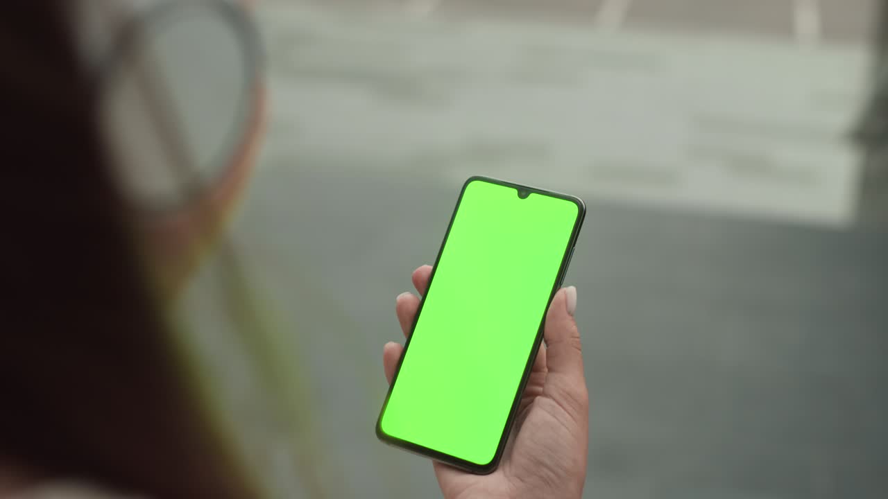 teléfono móvil en la mano con pantalla verde