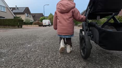 little child walking beside a stroller.