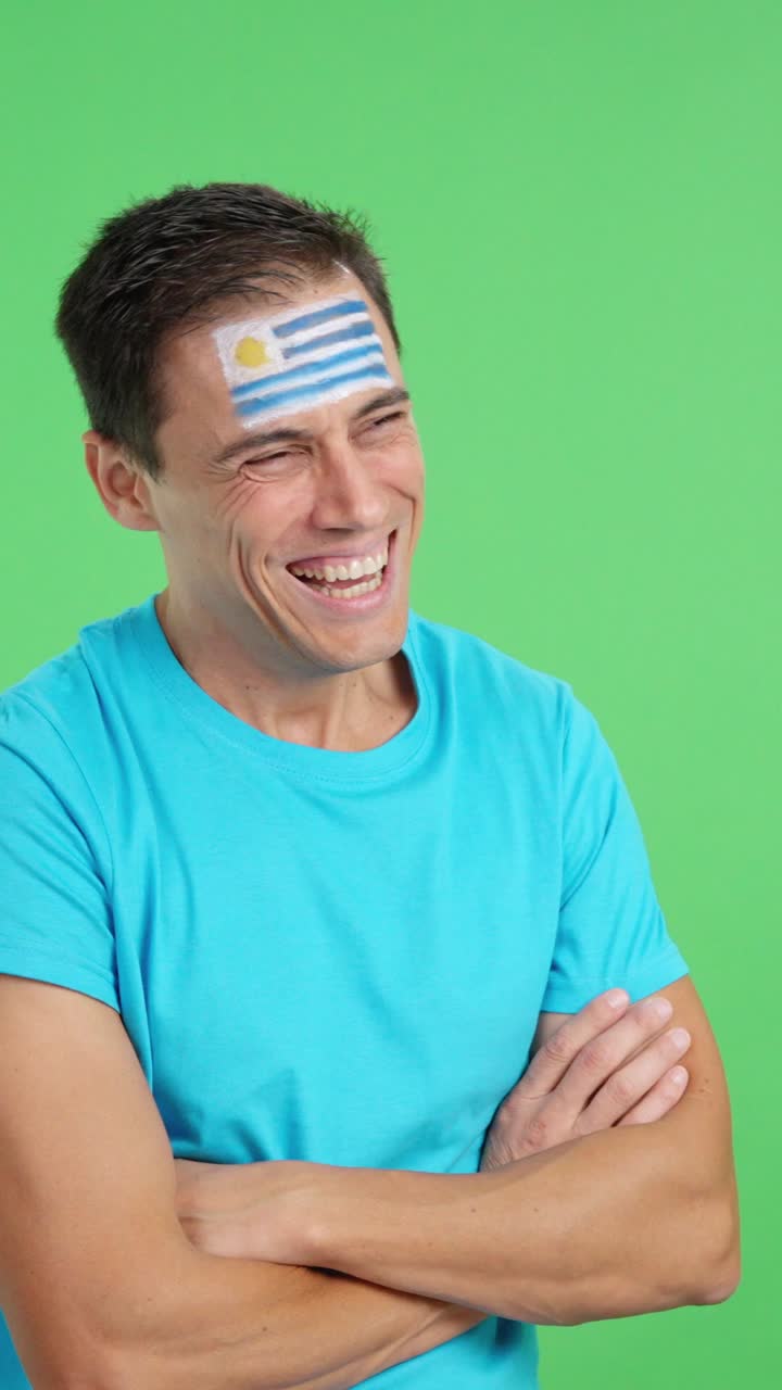 Happy man with uruguayan flag painted on face looking away