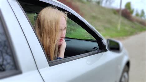 the blonde girl became ill from driving a car. vomiting forced her to look out of the car so that the vomit would not enter the passenger compartment. the girl suffers from kinetosis, motion sickness.