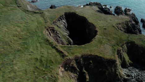 aerial orbiting shot or small crater near seaside cliff at day