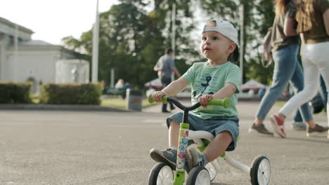 Focused-toddler-in-amusement-park.-Little-kid-making-first-try-on-bike-outside