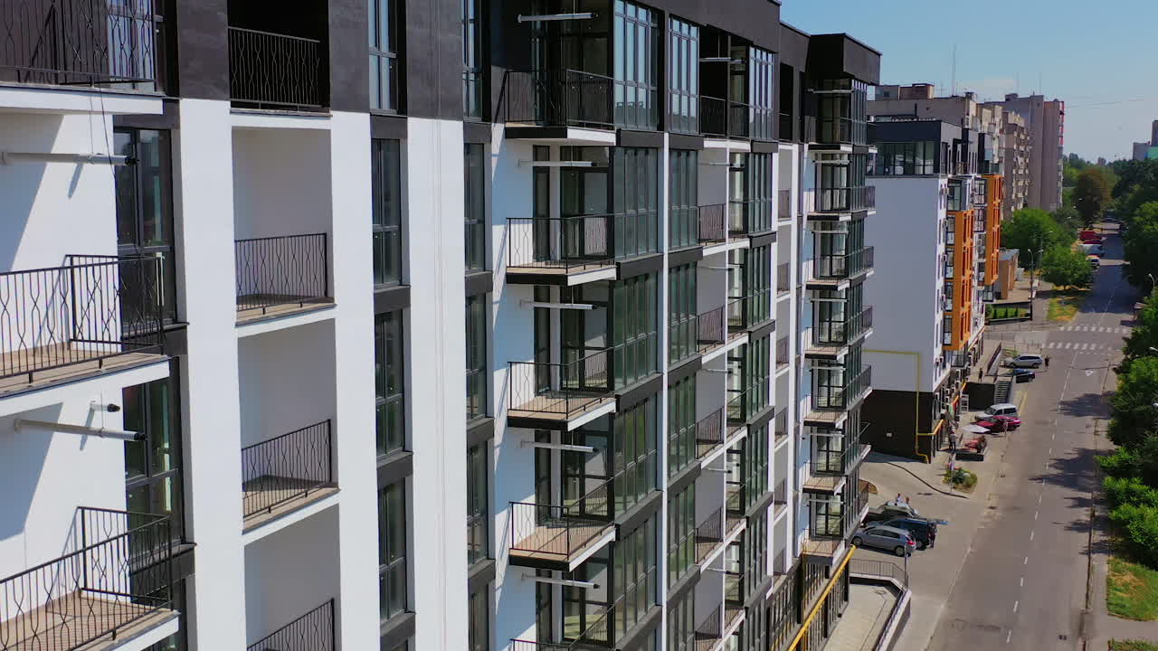 New architecture in the city. High-raise apartment buildings near the road. Modern design of multistorey building. Drone flight.