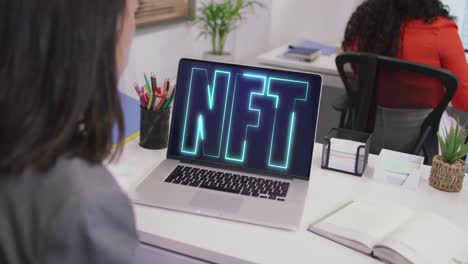 mujer de negocios biracial usando computadora portátil para videollamada con texto nft