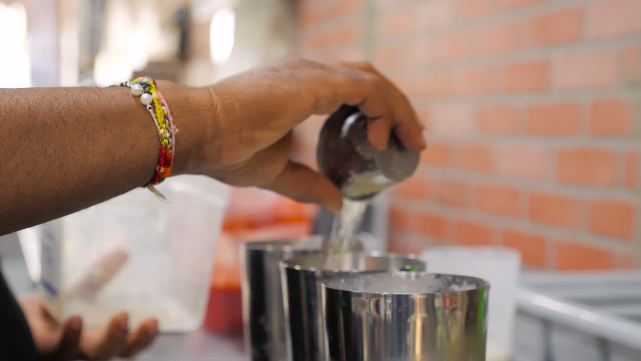Un barman versa zucchero negli shaker, prepara a mano tre bevande, ripresa ravvicinata con slider in slow motion -- 4K