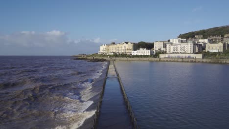weston super mare, somerset, england, december 22, 2019: waves crushing into artificial beach. tourist footpath flooded.