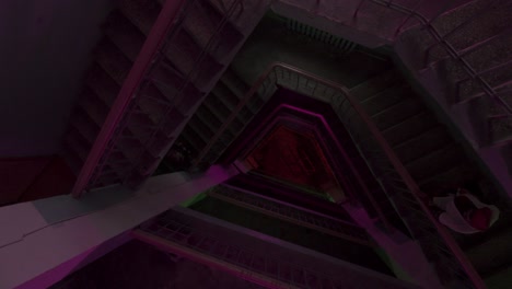 top view of a round shaped staircase under blinking lights of colorful bulbs. stock footage. flying down along stairs of a multi storey building, concept of party and music.