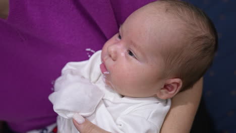 baby eating from a bottle and spilling some milk. caring mother cleaning spilled milk from baby's mouth and cheeks. close up.