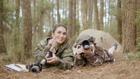 Caucasian-woman-and-her-son-birdwatching-while-lying-on-the-ground-in-the-forest