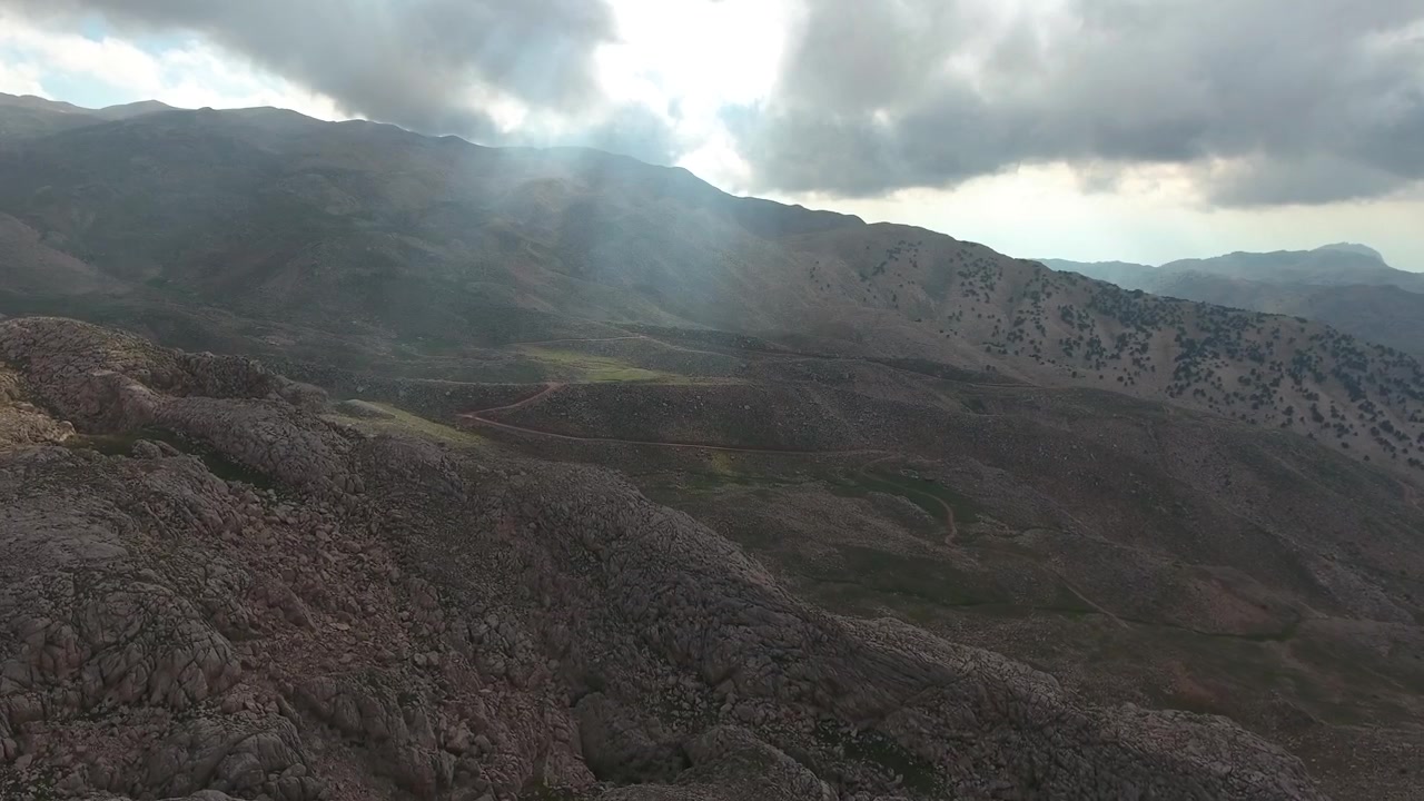 Vista aerea di paesaggio montano roccioso con raggi di sole che filtrano tra le nuvole