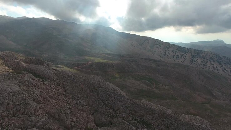 Vista aerea di paesaggio montano roccioso con raggi di sole che filtrano tra le nuvole