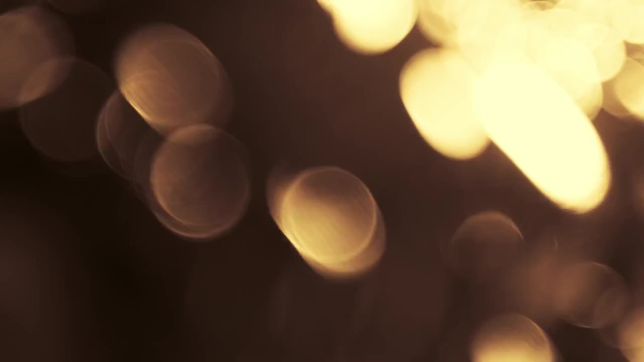 Particelle Bokeh Astratte di Luce Dorata Fluttuanti su Sfondo Nero