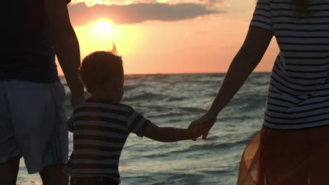 Family-looking-at-sunset-holding-hands