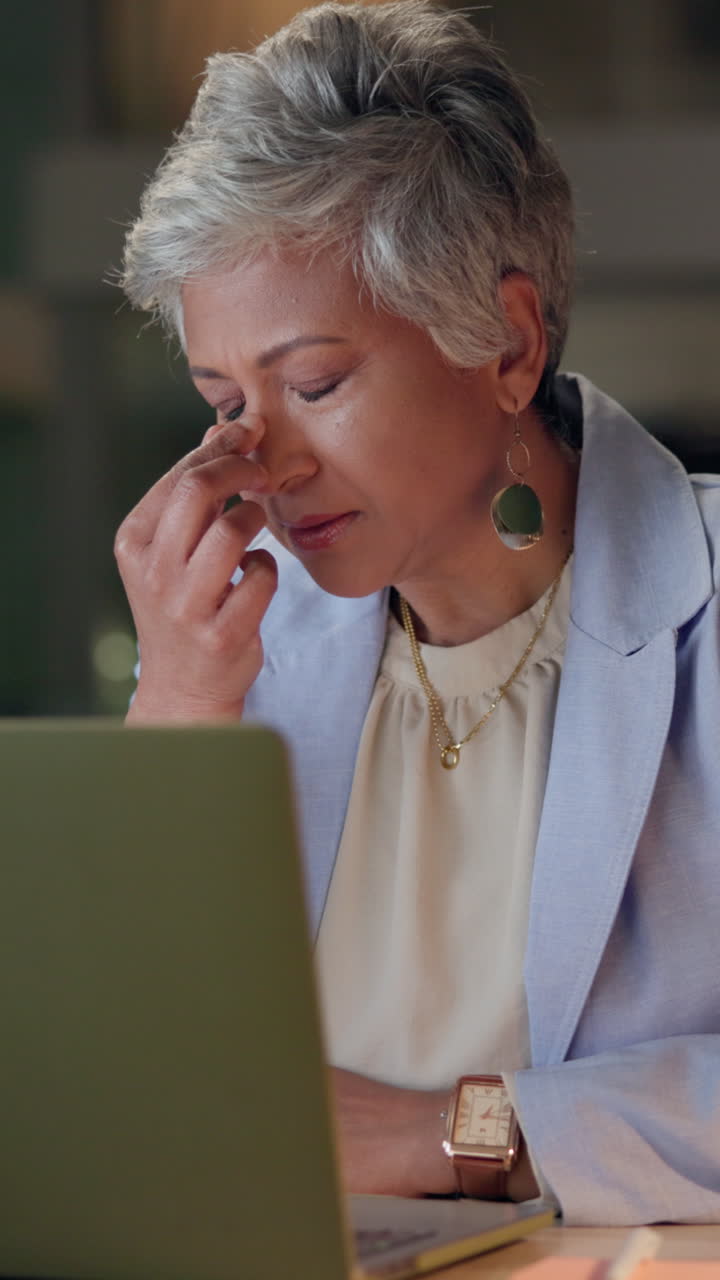 una mujer sentada en un escritorio, mirando preocupada mientras mira su computadora portátil.
