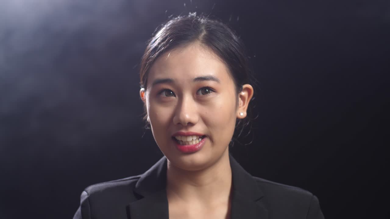 블랙 스크린 스튜디오에서 말하는 동안 지표손가락을 보여주는 비즈니스 슈트를 입은 아시아 스피커 여성의 클로즈업