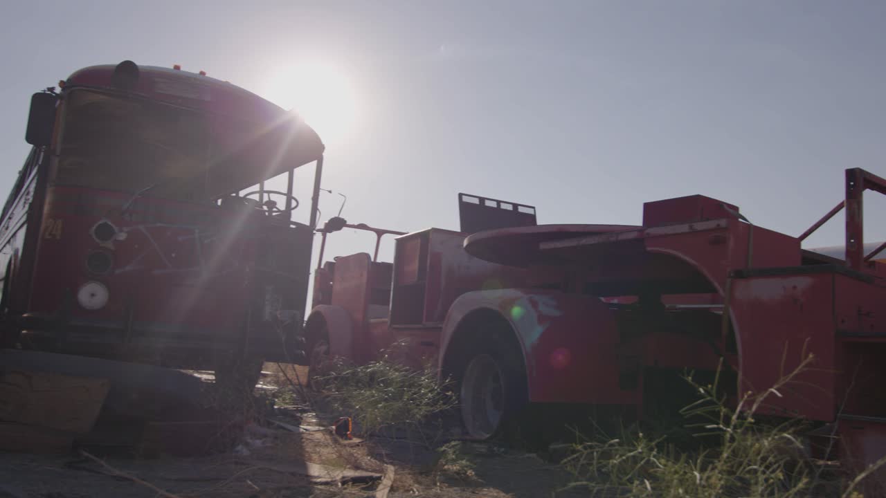 A collection of decrepit busses and vintage fire truck abandoned in the desert