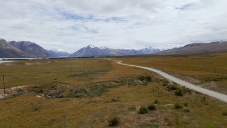 dusty dirt road within dry plains leading towards stunning snow covered mountains