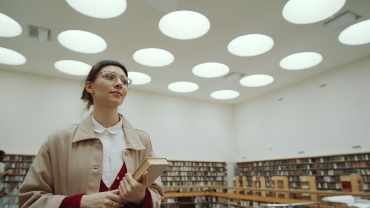 mujer con un libro y caminando por la biblioteca