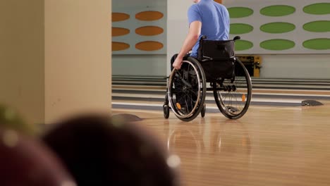 two young disabled men in wheelchairs playing bowling in the club